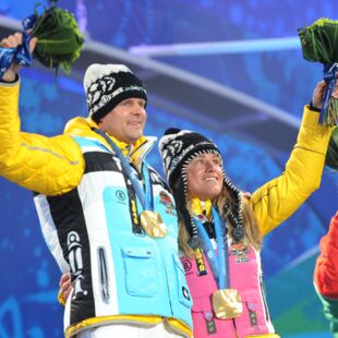 Paralympics Vancouver 2010_Siegerehrung_Thomas Friedrich und Verena Bentele haben eine Goldmedaille um den Hals und winken mit Blumenstrauss_Copyright dpa Picture Alliance GmbH Julian Stratenschulte